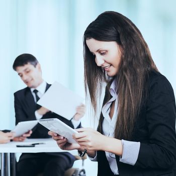 successful business woman studying a business plan of work in the office on the background of the work of his team