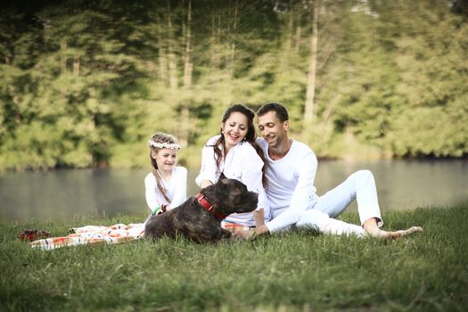 ,little daughter and their dog on a picnic by the river.the photo has a space for your text