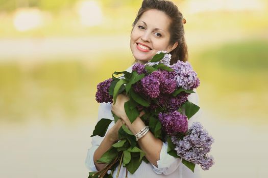 happy pregnant woman with bouquet of lilacs on the background of a Park in a autumn day. the photo has a empty space for your text