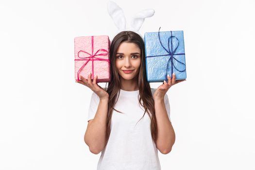 Celebration, holidays and presents concept. Portrait of adorable young woman in rabbit ears, holding two boxes with gifts, smiling camera, hurry up to congratulate friend on birthday party.