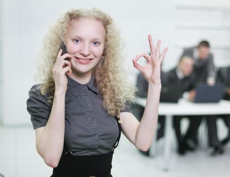 young female assistant showing OK sign,standing in the office.photo with copy space