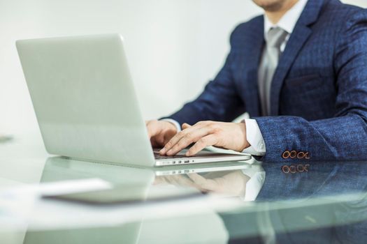 closeup - a successful businessman working on laptop in the workplace.the photo has a empty space for your text