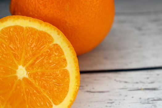 A slice of orange and a whole orange close-up on a wooden table..