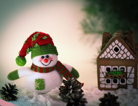 toy snowman and a gingerbread house on a light background. photo with copy space.