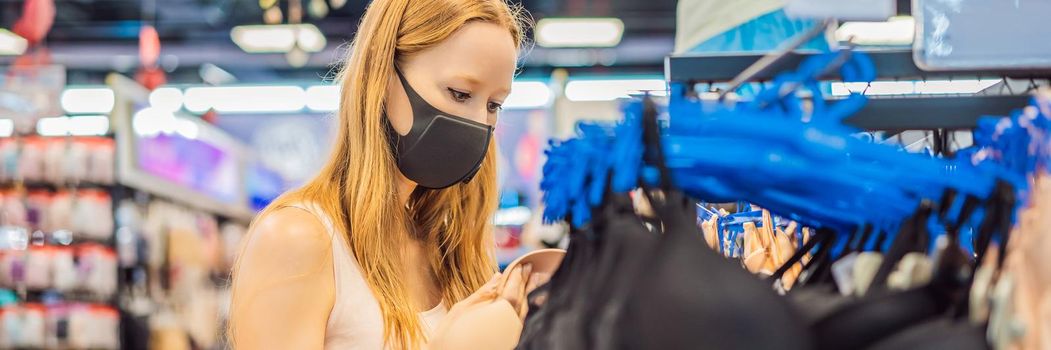 Woman in a clothing store in a medical mask because of a coronovirus. Quarantine is over, now you can go to the clothing store. BANNER, LONG FORMAT