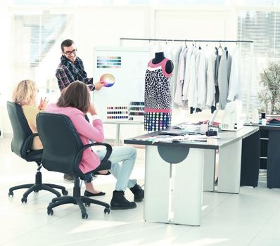 modern designer and his team choose the fabric for clothes in the office