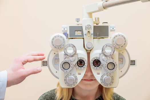 A male ophthalmologist checks a girl's eyesight using a phoropter. Vision treatment.