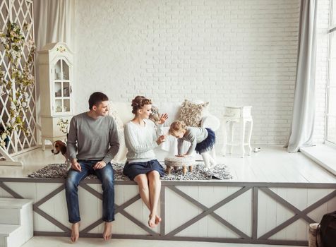 happy parents with five-year-old daughter and their pet dog in the cosy living room