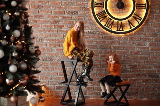 pretty sisters sitting in a stylish living room on Christmas eve . the concept of Christmas