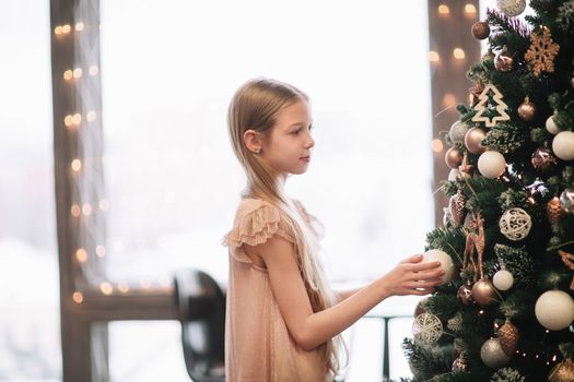 cute girl looking at the Christmas tree in her room . holiday concept