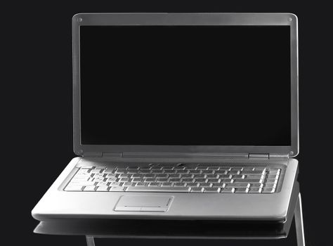 close up. open laptop with blank screen on a dark background.