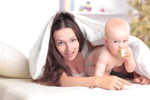 happy mother plays with the baby lying on the bed . the concept of education