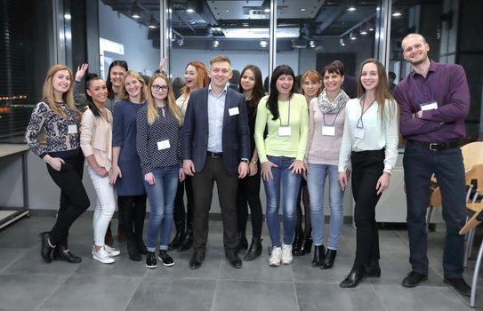 group of participants of the seminar with the badges on the backdrop of the conference hall