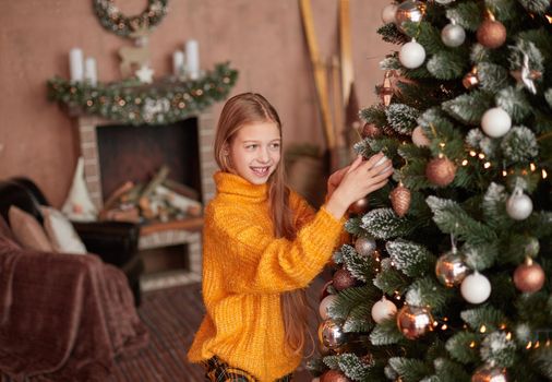 smiling teen girl decorating Christmas tree in her living room . the concept of Christmas