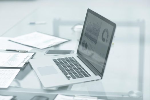 laptop, clipboard and financial data on the businessman's Desk.