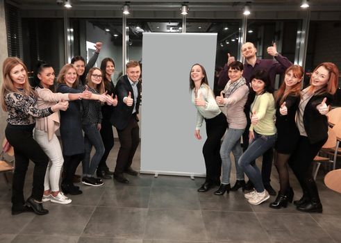 business team standing in front of a large banner and showing thumb up.the concept of success.