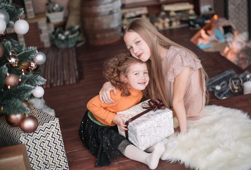 two pretty sisters sitting on the floor on Christmas eve. holiday concept