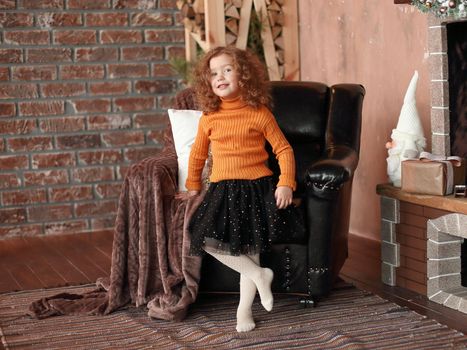little girl standing by the fireplace and pointing at you . holiday concept