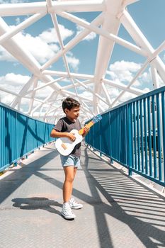 Latin boy playing a ukulele in the middle of a bridge in Managua Nicaragua