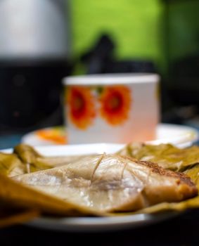 Stuffed tamale served on wooden table, stuffed tamale on banana leaf served on wooden table, typical nicaragua food