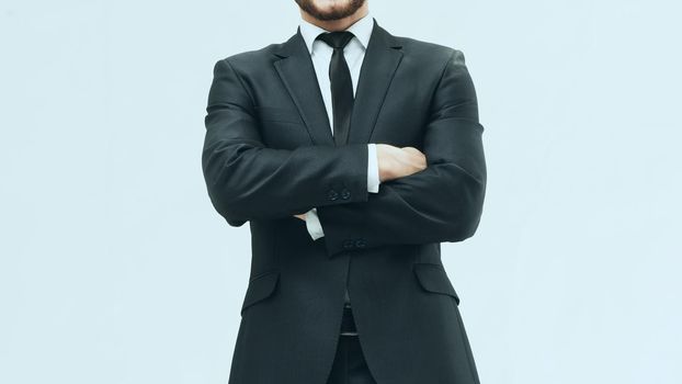 smiling businessman in a stylish suit and tie standing with crossed legs