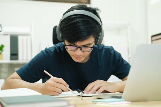 Young male student study at home. He using laptop and learning online.
