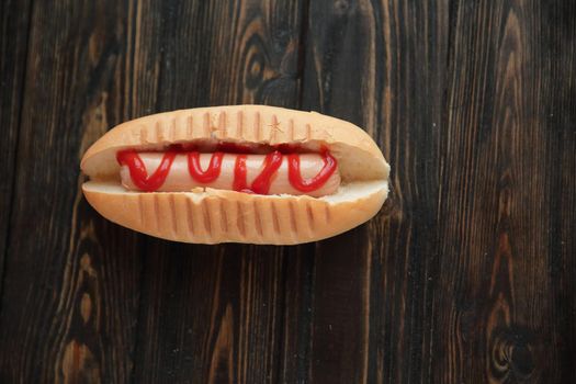 hotdog with tomato sauce on dark wooden background.photo with copy space.