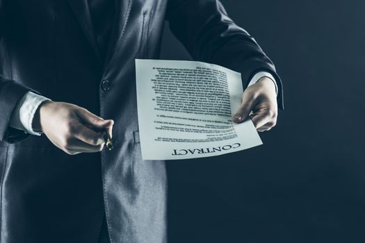 businessman holding a pen and a document with the terms of the contract.photo on a black background and has space for your text