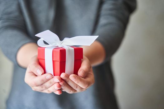 Woman holding small red present box in hands. High-quality photo