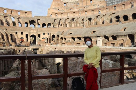 ROME, ITALY - February 05, 2022: Panoramic view around the Colosseum in city of Rome, Italy. Cold and gray sky in the background. Macro photography of the green parks with the old buildings.