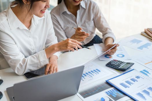 Negotiation, Analysis, Discussion: Asian female economist and marketer pointing to a financial data sheet to plan investments to prevent risks and losses for the company.