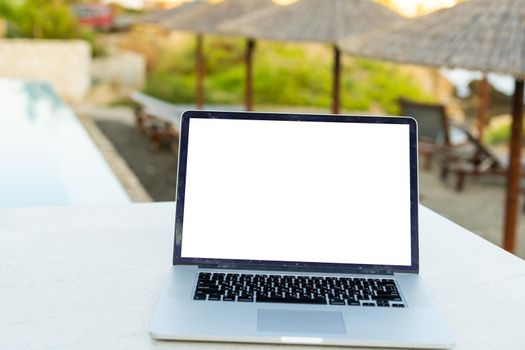 A laptop with an empty screen stands in the courtyard of a beautiful home garden, in Sunny weather