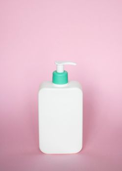 Large white plastic bottle with pump dispenser as a liquid container for gel, lotion, cream, shampoo, bath foam on pink background