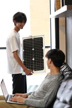 Young gay couple installing solar panels. Concept of Alternative renewable green energy, ecological renewable energy.