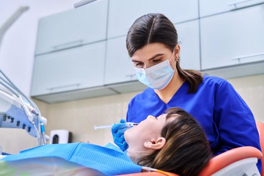 Doctor dentist treats teeth to a young teenage female patient. Real process of treatment, dental care, orthodontics, therapy, health care, dentistry concept