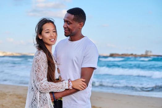 Beautiful young couple in love on beach. Portrait of Asian woman and African American man embracing. Multicultural, multiethnic family, relationships, togetherness, lifestyle, sea nature vacation