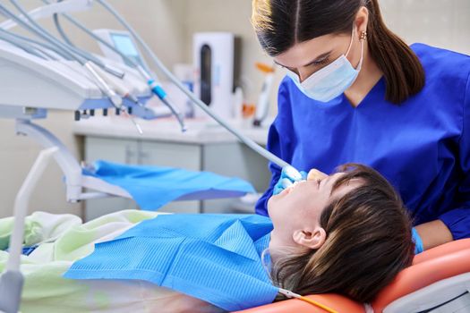 Doctor dentist treats teeth to a young teenage female patient. Real process of treatment, dental care, orthodontics, therapy, health care, dentistry concept