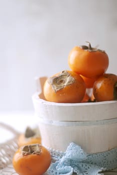 persimmons in a basket and scattered on the table. rustic style. High quality photo