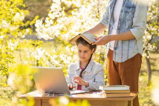 little girl with father studying on laptop outdoor.