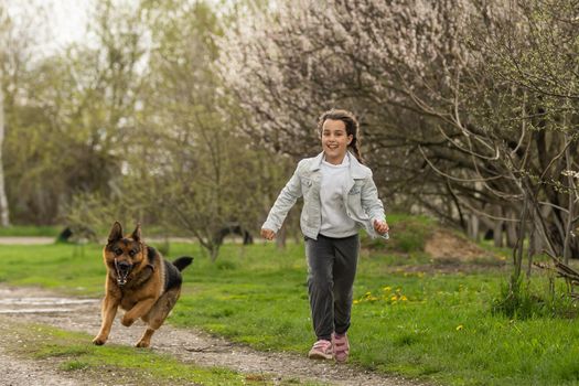 little girl running with a dog in a flower garden.