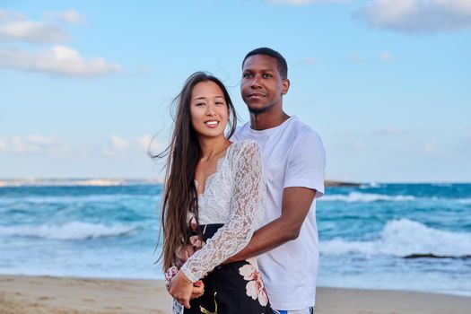 Beautiful young couple in love on beach. Portrait of Asian woman and African American man embracing. Multicultural, multiethnic family, relationships, togetherness, lifestyle, sea nature vacation