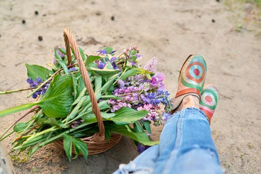 Spring fresh flowers in a basket on the ground with legs close up, top view. Beauty, season spring summer, nature, flower arrangement