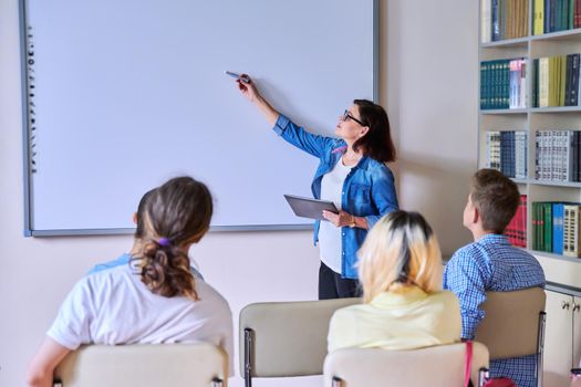 Lesson in classroom with digital screen for group of teenagers. Teaching, discussion with teenage students. Technology, education, knowledge, high school, college, youth concept