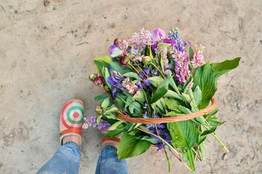 Spring fresh flowers in a basket on the ground with legs close up, top view. Beauty, season spring summer, nature, flower arrangement