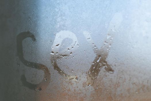 Sex inscription on the sweaty glass with drops dripping condensate. Concept photo of sex in the bathroom.