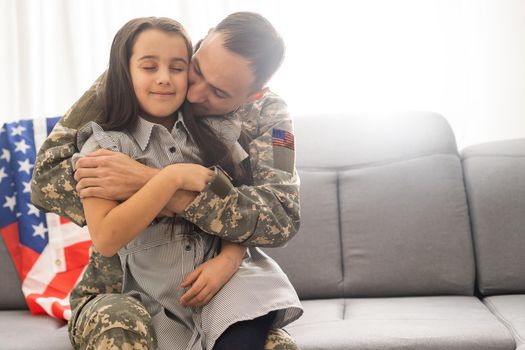 Little child is very happy her father came back from army. Little kid is hugging her father
