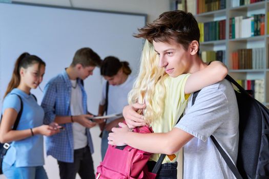 Teenage friends students hug when meeting each other in the library. Cheerful smiling high school students, educational institution, adolescence, education, friendship communication concept