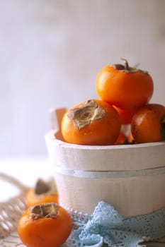 persimmons in a basket and scattered on the table. rustic style. High quality photo