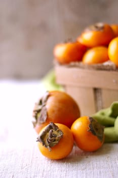 persimmons in a basket and scattered on the table. rustic style. High quality photo