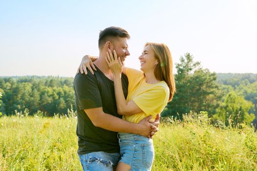 Outdoor portrait of happy middle age couple in love embracing, background summer nature of wild meadow. People 40s, family, relationships, leisure, holidays, lifestyle concept